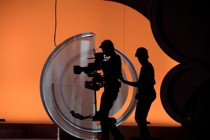 silhouette of students with cameras in front of orange background
