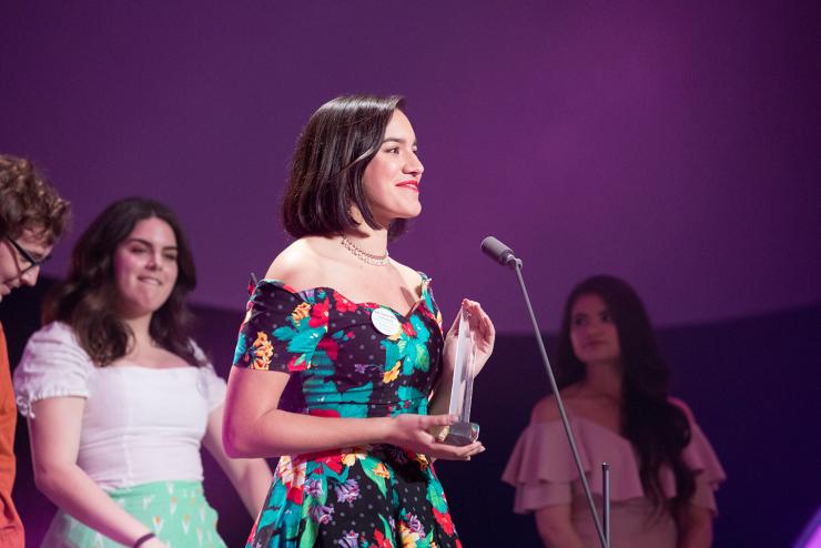Student smiling and accepting an award on stage at Evvy awards ceremony