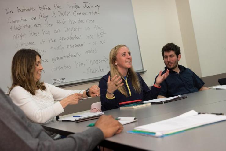 Students conversing at a conference table in a classroom