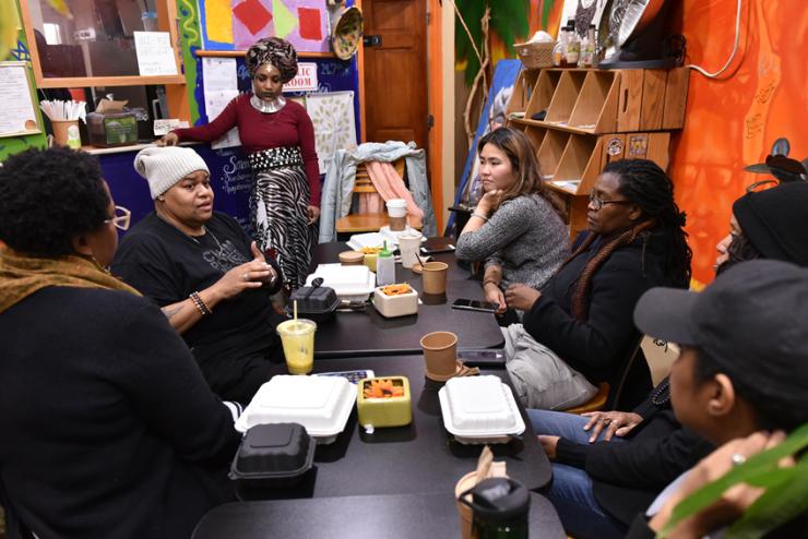 Boston artists (left to right) Latifa Ziyad, Nahdra Ra, Ngoc-Tran Vu, Letta Neely, Melissa Alexis and Kendra Hicks meet with Toshi Reagon (second from left) at Dorchester’s Oasis Vegan Veggie Parlor to discuss the Parable Path Boston. (Photo: Craig Bailey/Perspective Photo)