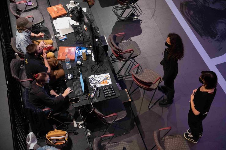 Overhead view of three students sitting at a table full of tech equipment and books