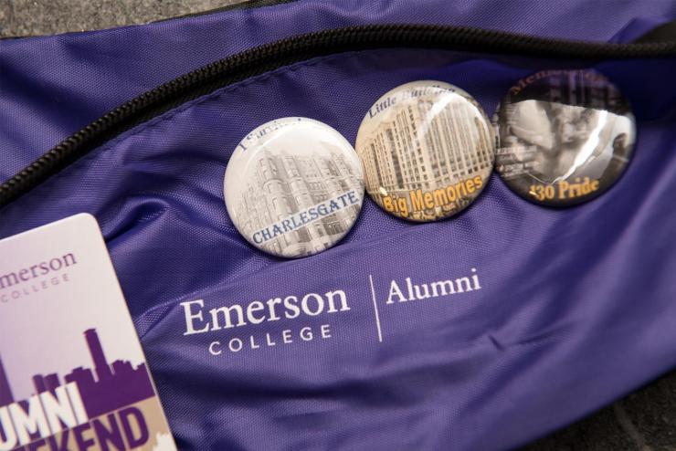 Three round buttons with Boston imagery pinned to a purple, Emerson-branded fanny pack