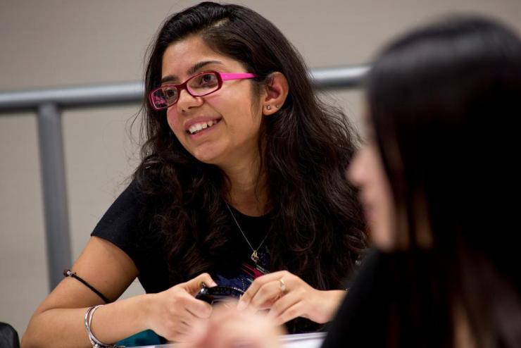 A student with pink glasses smiling in a classroom