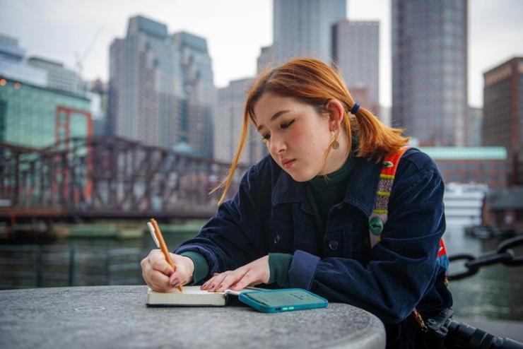 Student writing in a notebook outdoors in Boston
