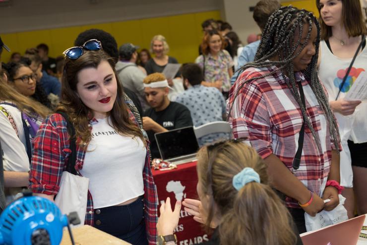 In a busy room, diverse Emerson students excitedly visit organizations’ tables