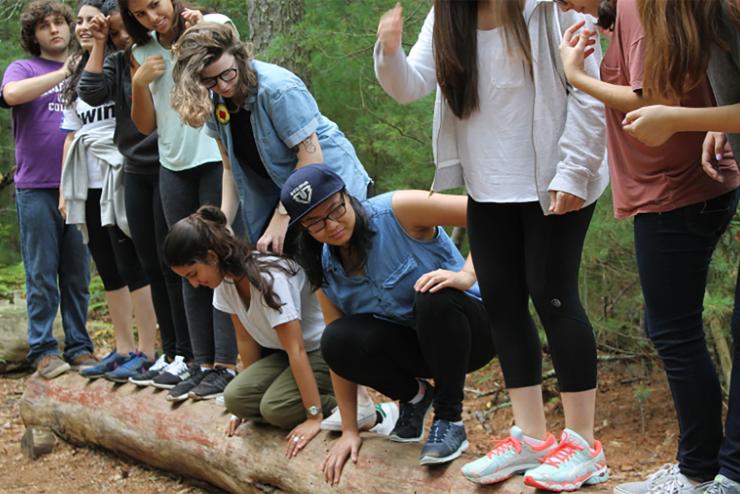 Students participating in an outdoor game while balancing on a log