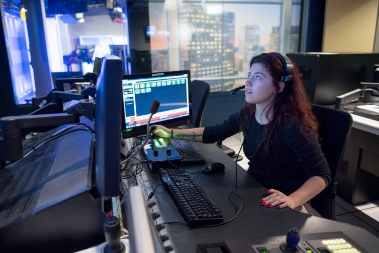 Journalism student working at a broadcast dashboard, supervising multiple monitors