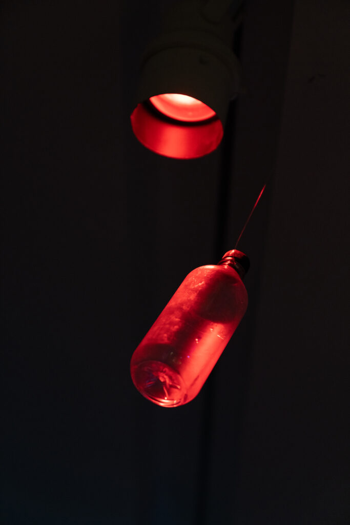 A dark image with a silhouette of a red microphone