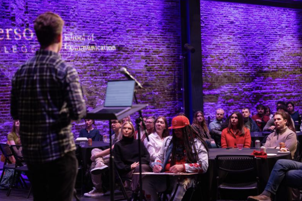 An audience looks on while a person is talking