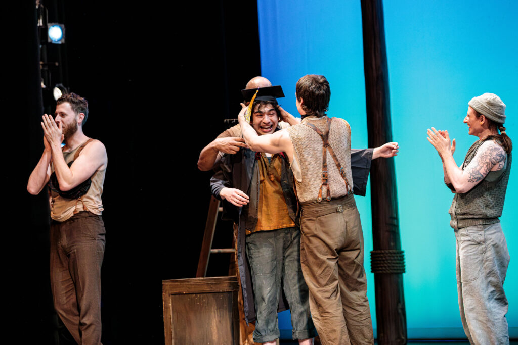 Nicholas Papayoanou ’26 reacts with surprise as he receives his Emerson College diploma during the curtain call for Swept Away.