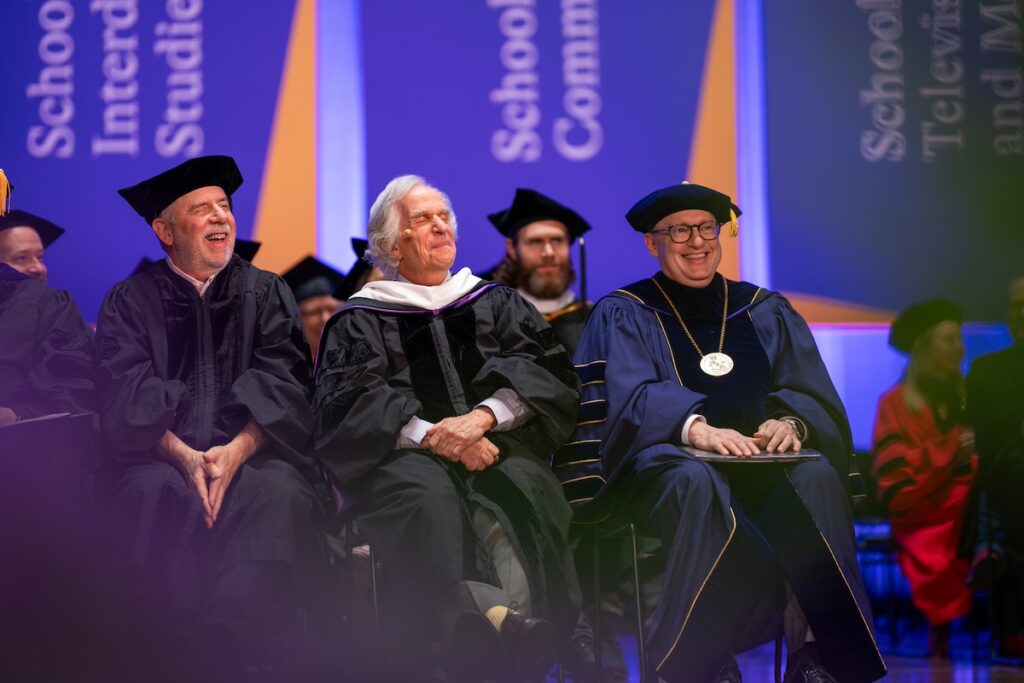 three people sit on stage