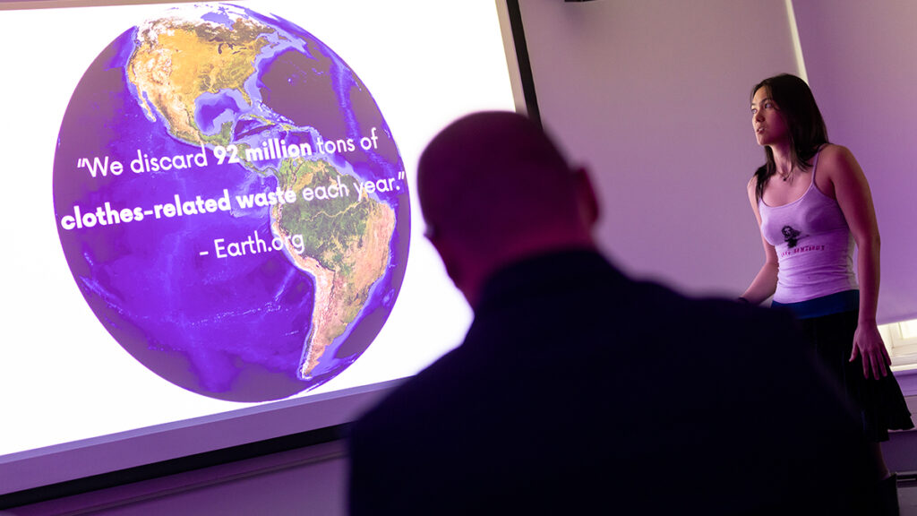 Student presents in front of screen showing a photo of Earth
