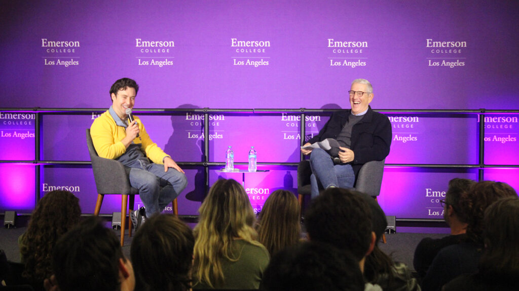 Brian Jordan Alvarez speaks into a mic while seated on stage with Doug Herzog