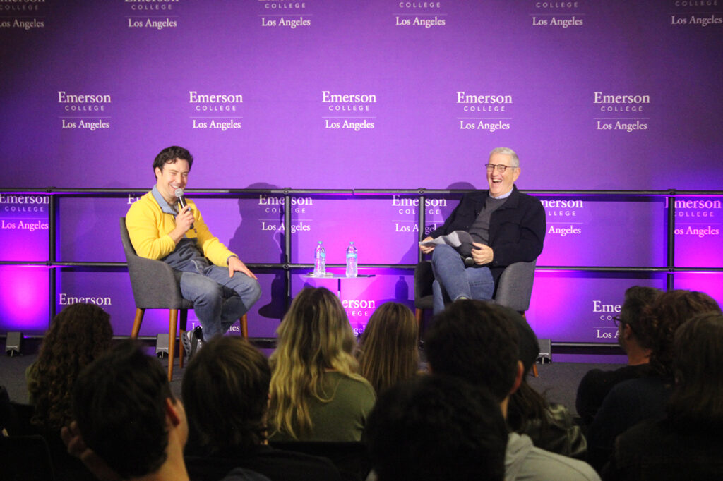 Brian Jordan Alvarez speaks into a mic while seated on stage with Doug Herzog
