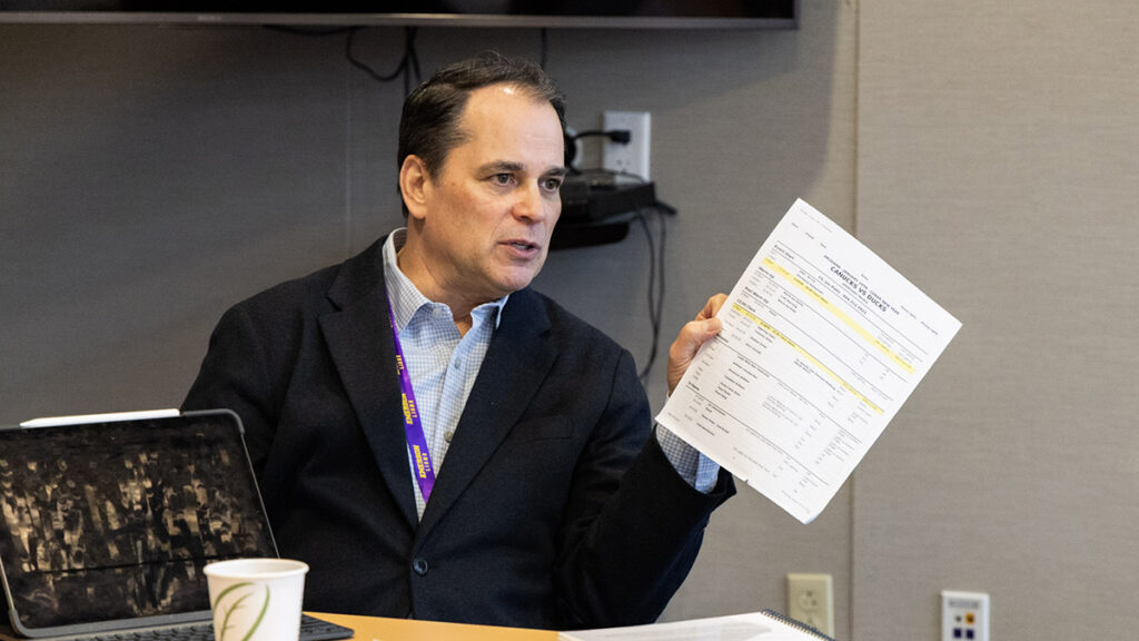Tim Neverett holds a piece of paper while talking|