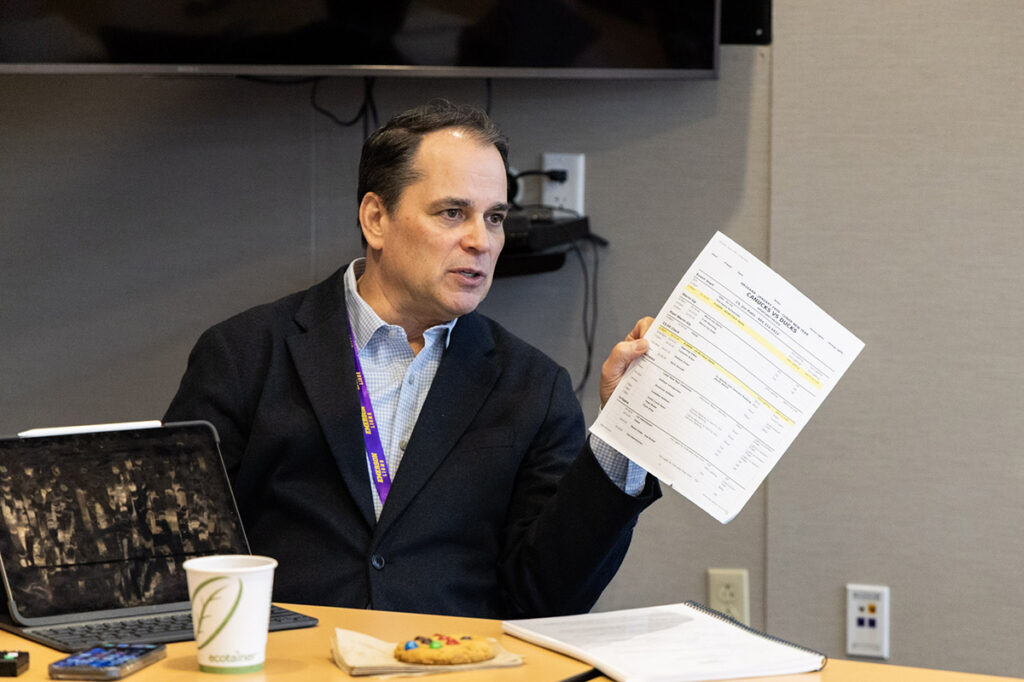 Tim Neverett holds a piece of paper while talking|