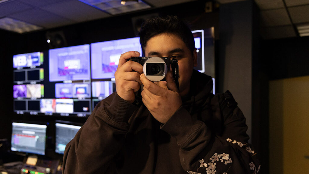 Marcos Quinones holds a camera to his face||