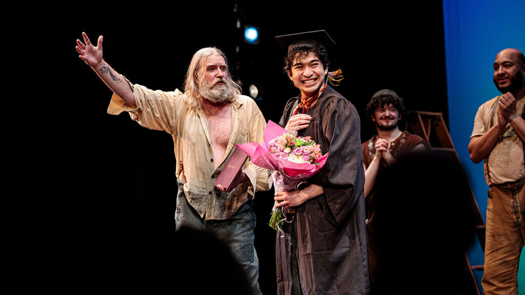 Nicholas Papayoanou reacts with surprise as he receives his Emerson College diploma during the curtain call for Swept Away.||