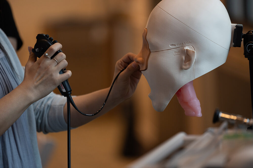 hands manipulate cord through nose of a dummy head