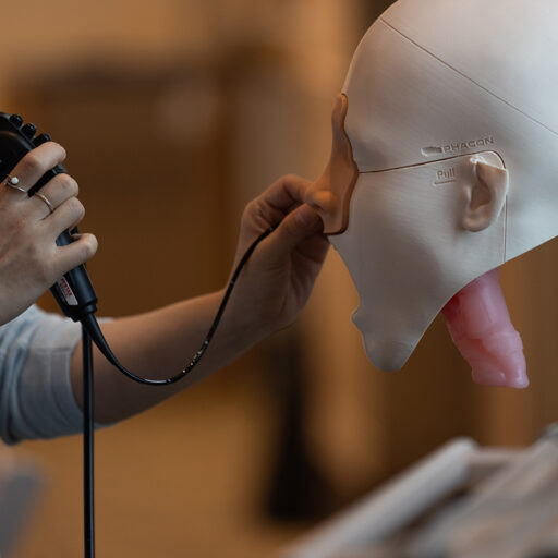 hands manipulate cord through nose of a dummy head