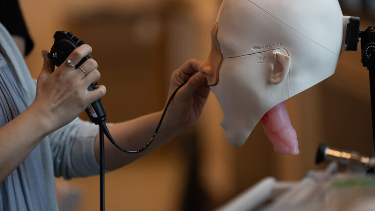 hands manipulate cord through nose of a dummy head