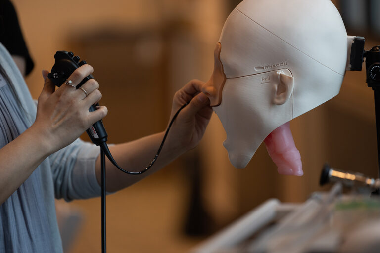 hands manipulate cord through nose of a dummy head