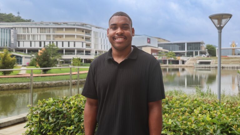 Man stands in front of canal, buildings