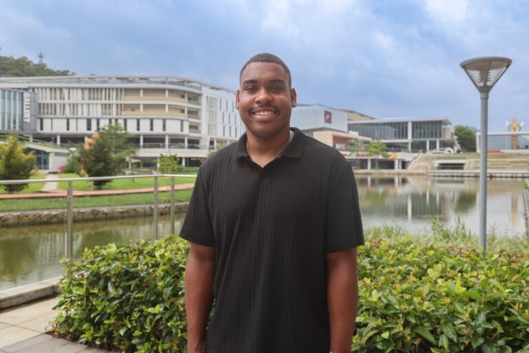 Man stands in front of canal, buildings