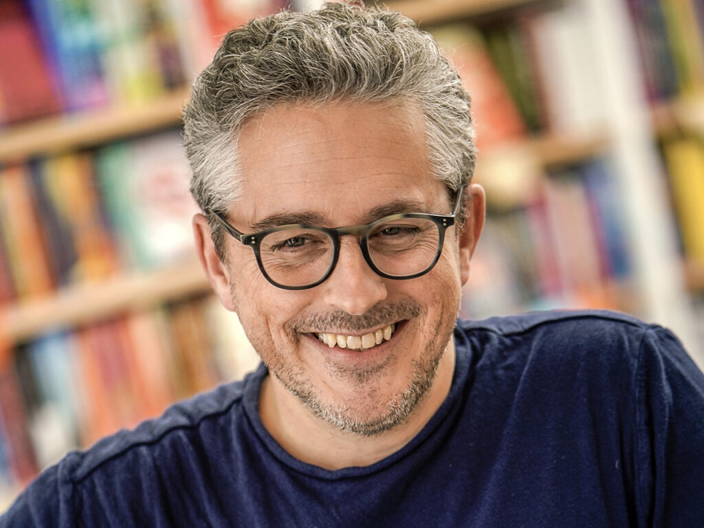 Alex George in front of book shelves