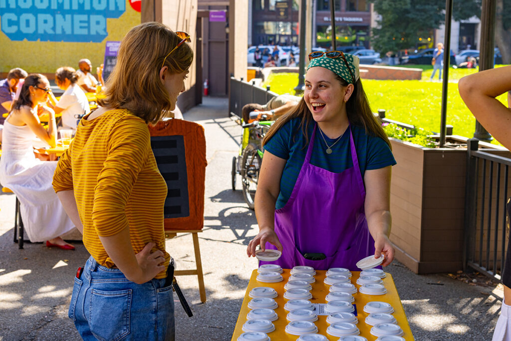 Student smiles while standing over a tray of fake coffee cups