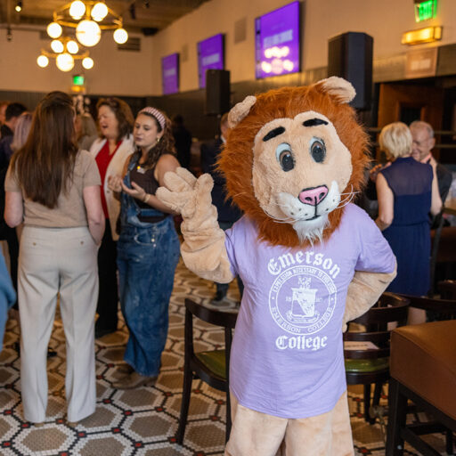 Person in lion costume and Emerson t-shirt waves at gathering