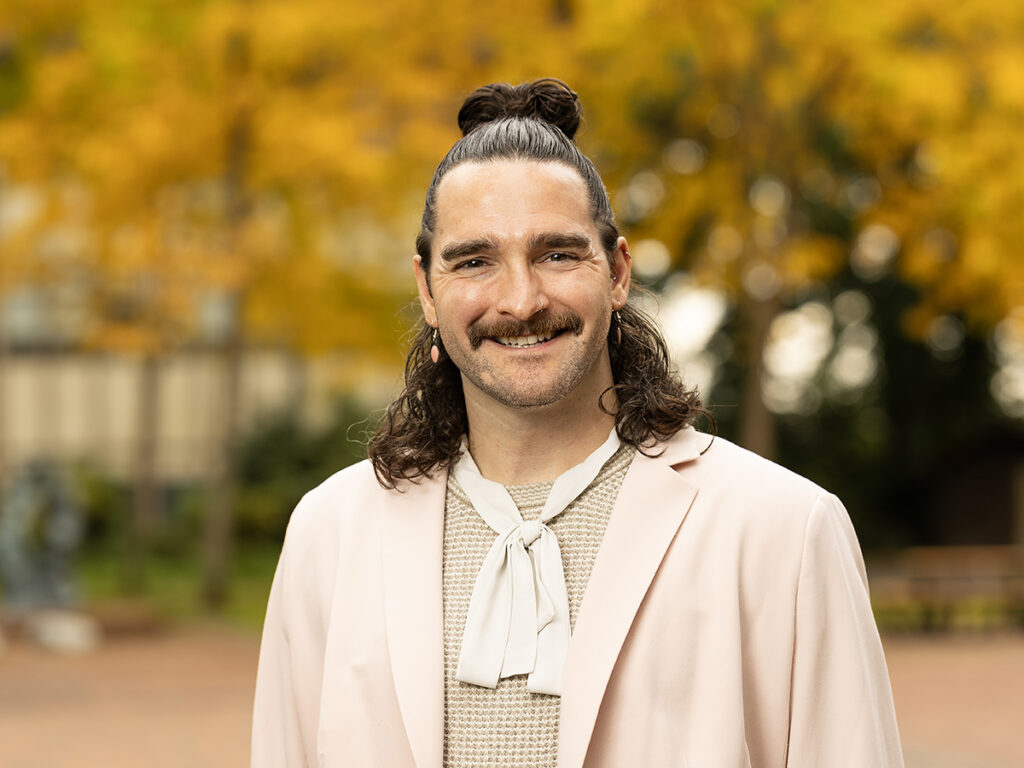 Smiling man with long hair and mustache in casual attire
