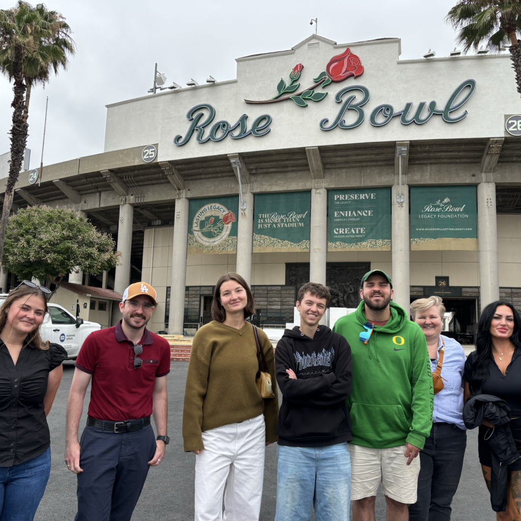 Several people pose for a photo in front of Rose Bowl Stadium