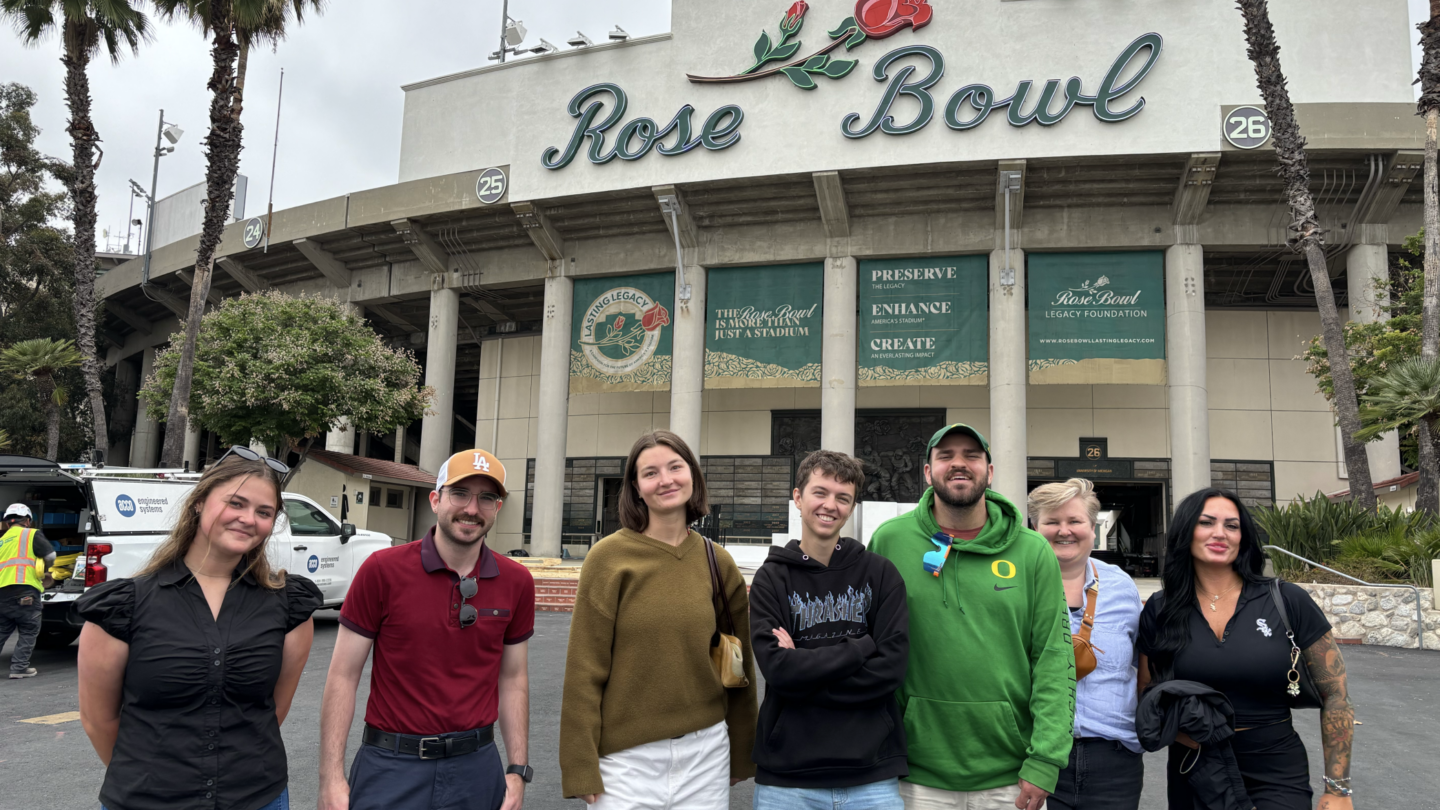 Several people pose for a photo in front of Rose Bowl Stadium