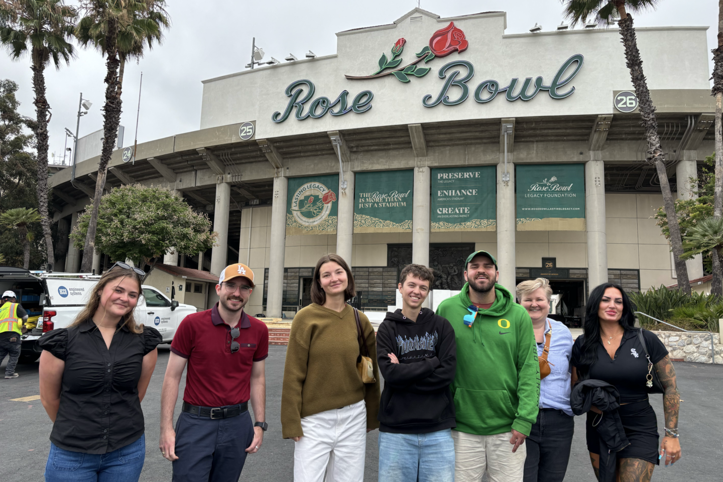 Several people pose for a photo in front of Rose Bowl Stadium
