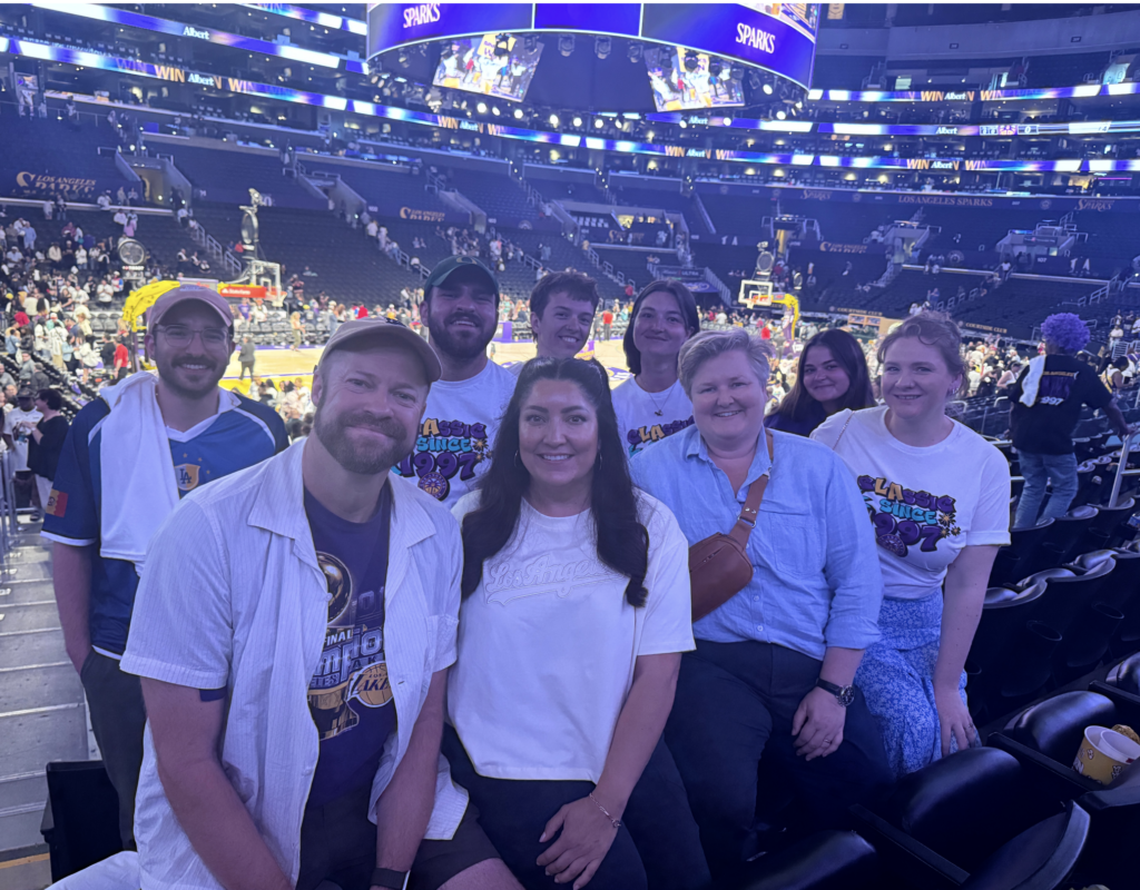 A group of people pose for a photo at the LA Sparks game with the court behind them