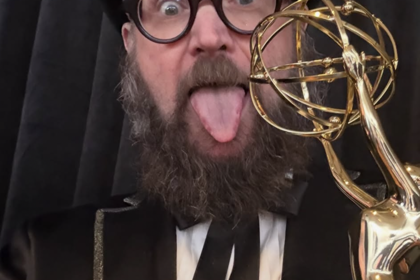 Opus Moreschi sticks out his tongue while holding an Emmy Award