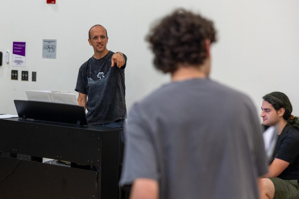 Jason Lytle points during a rehearsal from behind a piano