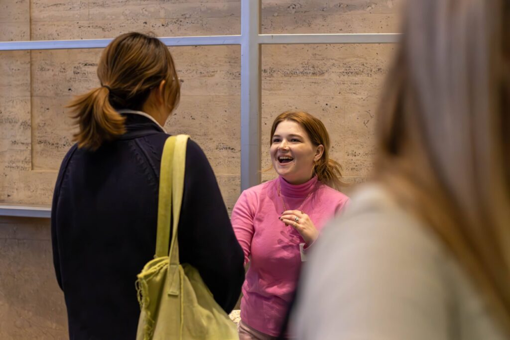 A woman smiles as she speaks with a student who is not facing the camera