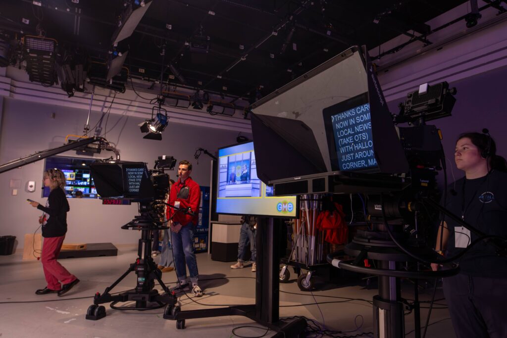 Several people working behind cameras and in the production room