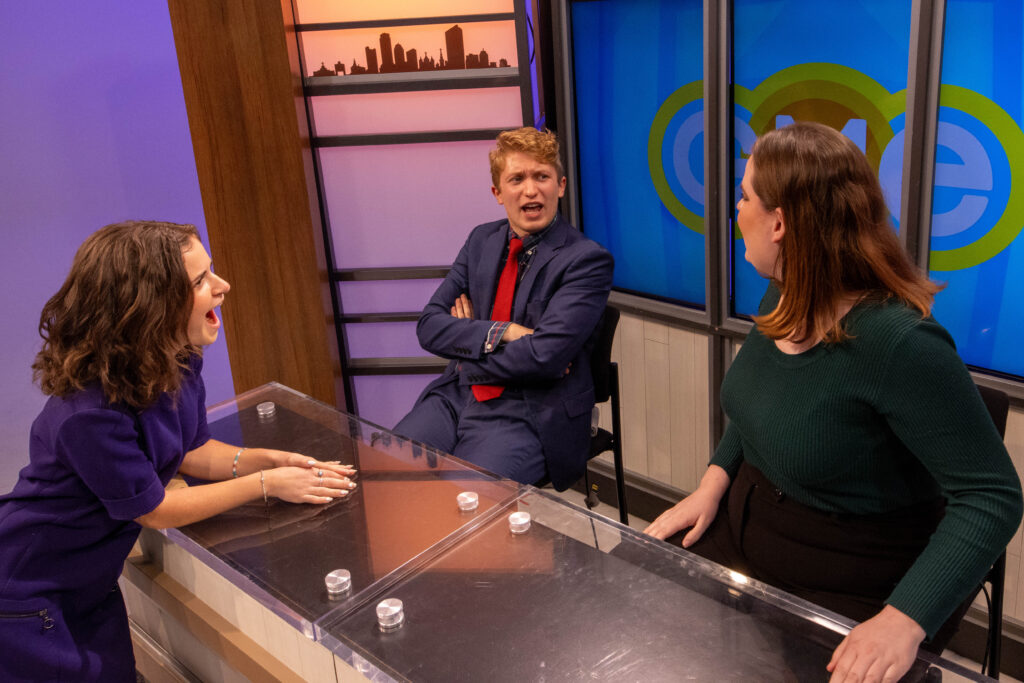 Three people smile and laugh around a table