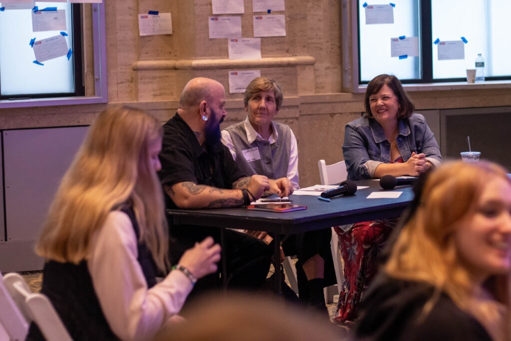 Three judges sit at a table and discuss submissions