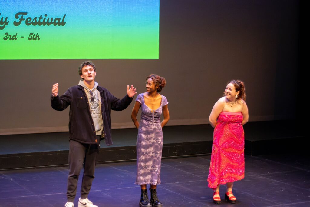 Three people stand on stage