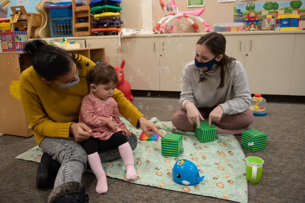 A child sits on an adult's lap while another person sits near them