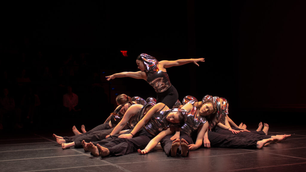 One person stands with their arms spread out while others lay near their feet