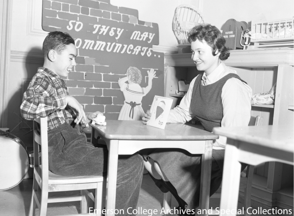 A speech clinician holds up a flashcard in front of a boy
