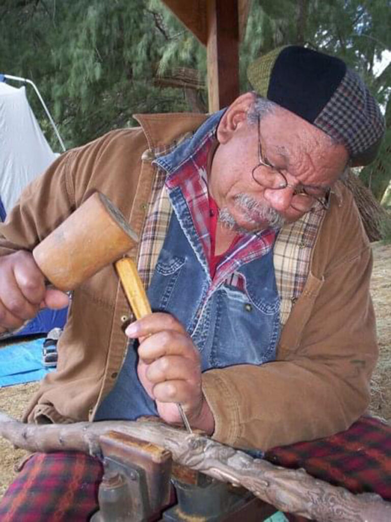 Pierre Desir chisels a piece of wood