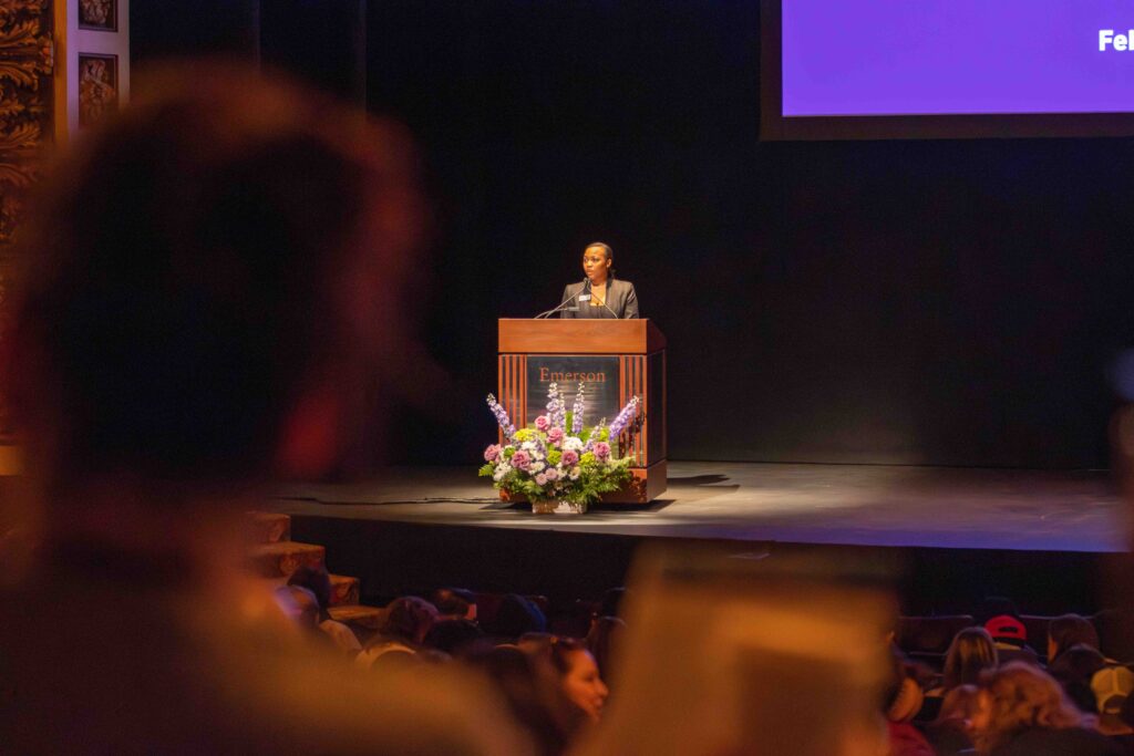 A faraway view of a person talking in front of a lectern on stage