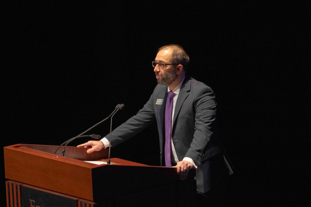 Justin Sharifipour speaks to the audience behind a lectern