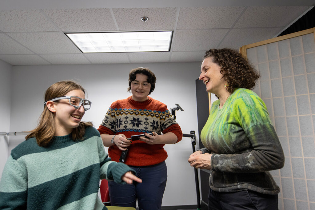 Grossman and two students chat animatedly in the FACE Lab